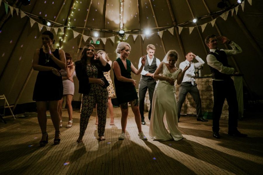 Guests mid-dance under string lights at a reception.