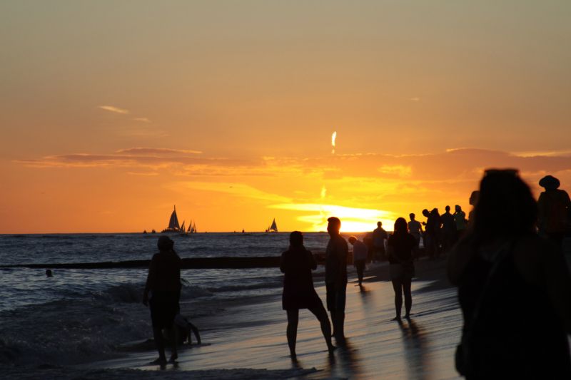 Silhouettes of people celebrating on a beach at sunset.