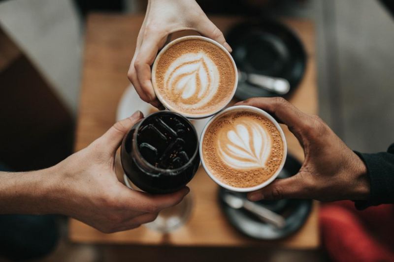 Colleagues clinking coffee cups together over a table.